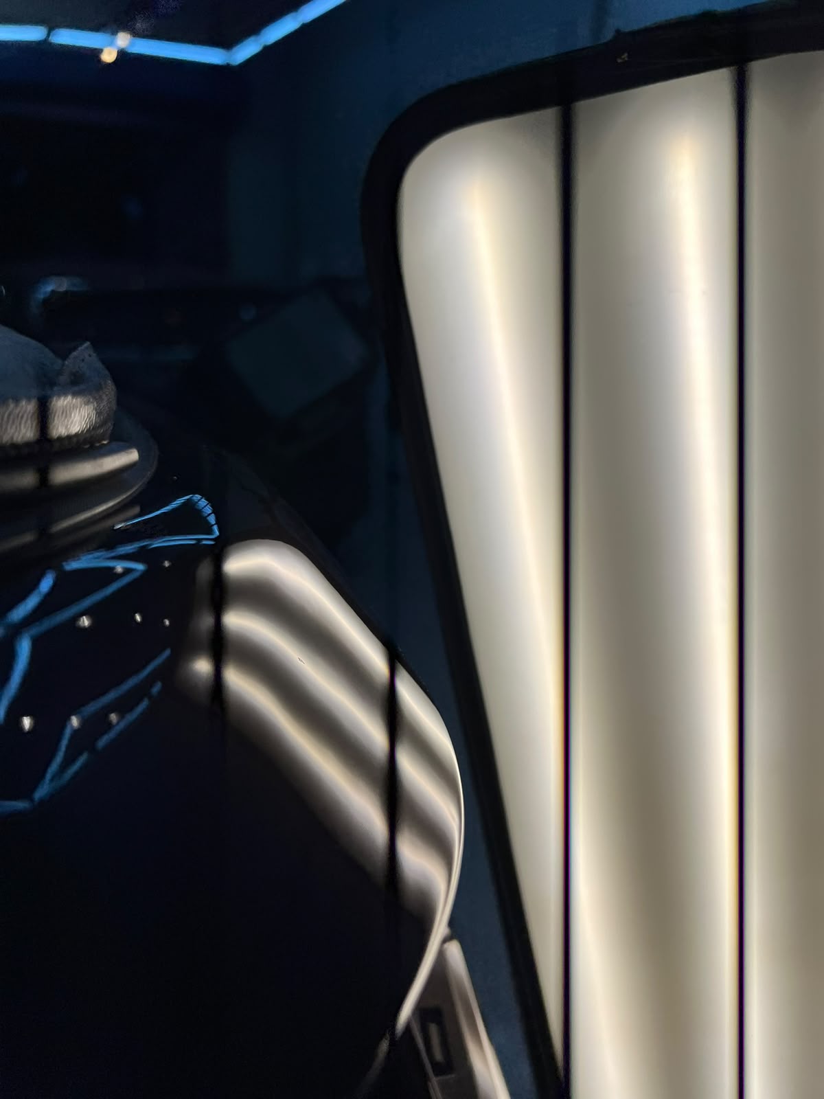 Lateral direita azul-escura de um carro com as listras da régua de luz refletidas retas e paralelas sobre a pintura, depois do reparo